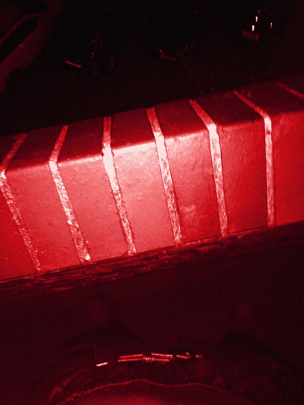 Looking down at red shoes on the pavement beside a brick wall.