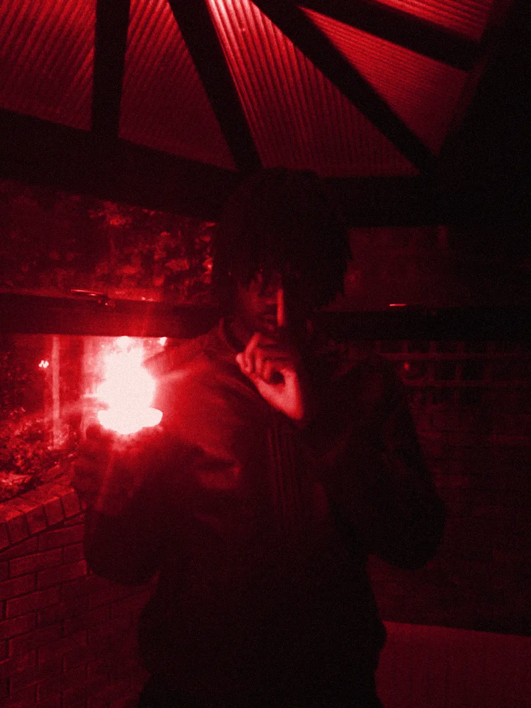 Under a glass roof at night, the flame lighting his hand.