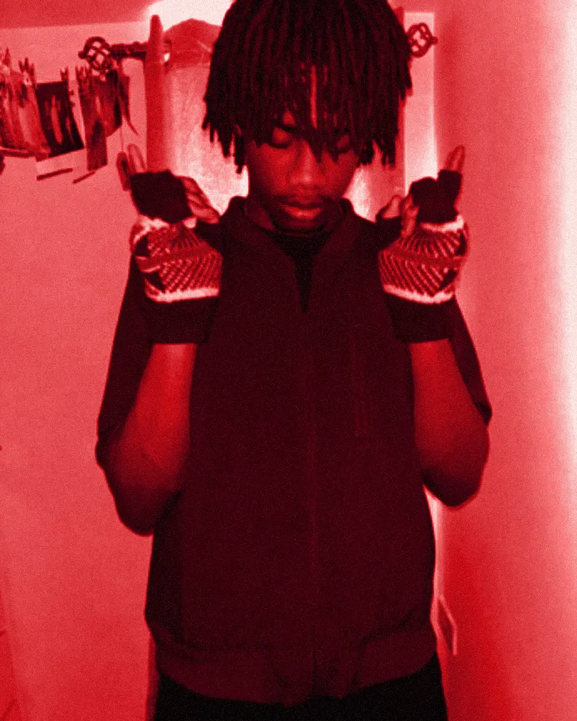 yukan with purple-tipped locs in a maroon track jacket, patterned gloves framing his face.