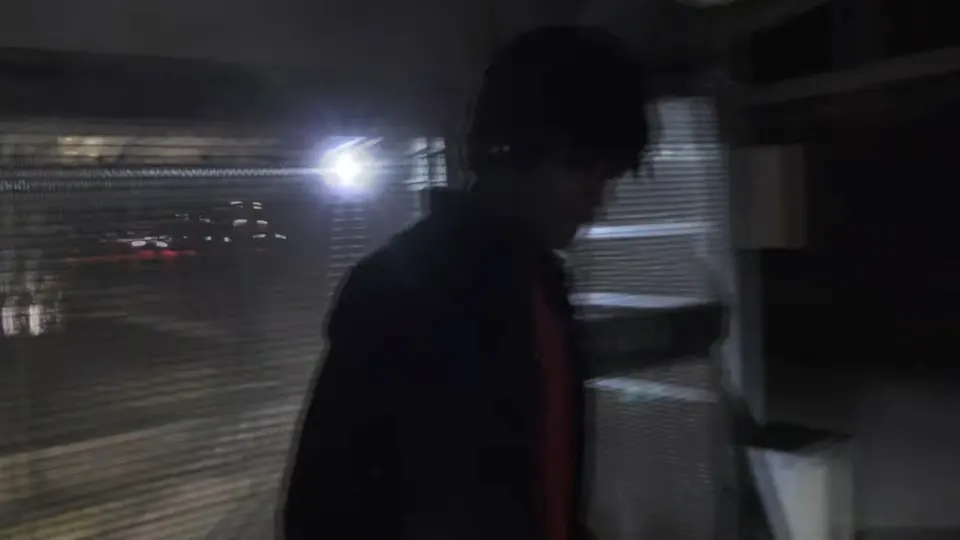 Still from the Fake ID video: a figure in a dark car park against a flash of light.
